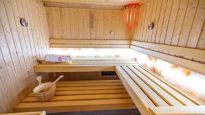 Una sauna de madera con bancos y un cubo de madera.