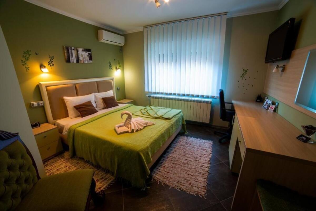 A bedroom with a bed, bedside tables, a desk, and a television.