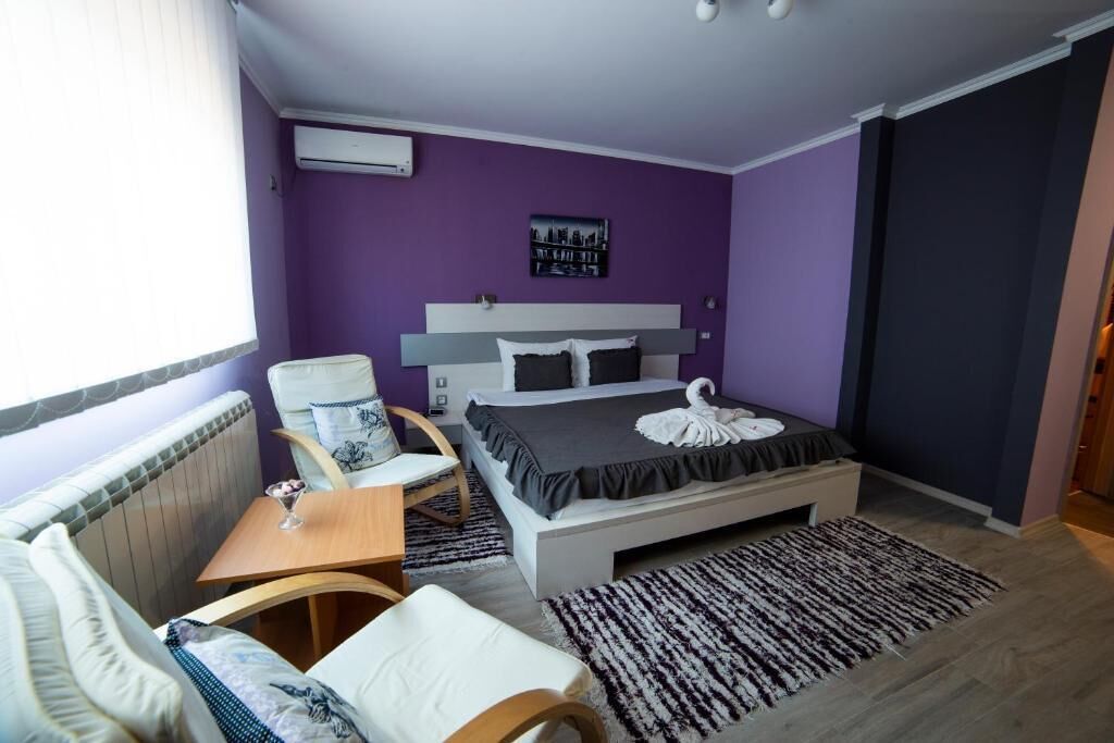 A modern bedroom with a bed, a chair, a small table, and a radiator.