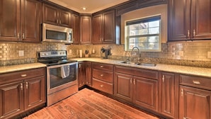 A kitchen with dark wood cabinets, a stainless steel microwave, oven, and sink.