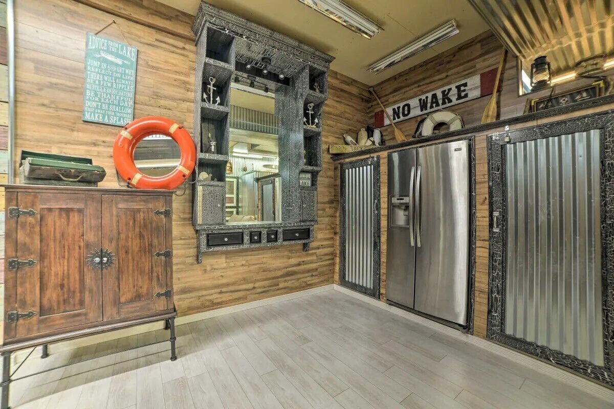 Cocina con paredes de madera, espejo de marco metálico, electrodomésticos de acero inoxidable y un letrero que dice 'NO WAKE'.