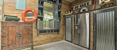 Cocina con paredes de madera, espejo de marco metálico, electrodomésticos de acero inoxidable y un letrero que dice 'NO WAKE'.