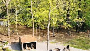 A rustic outdoor area with a wooden cabin, a fire pit, and a gravel path.