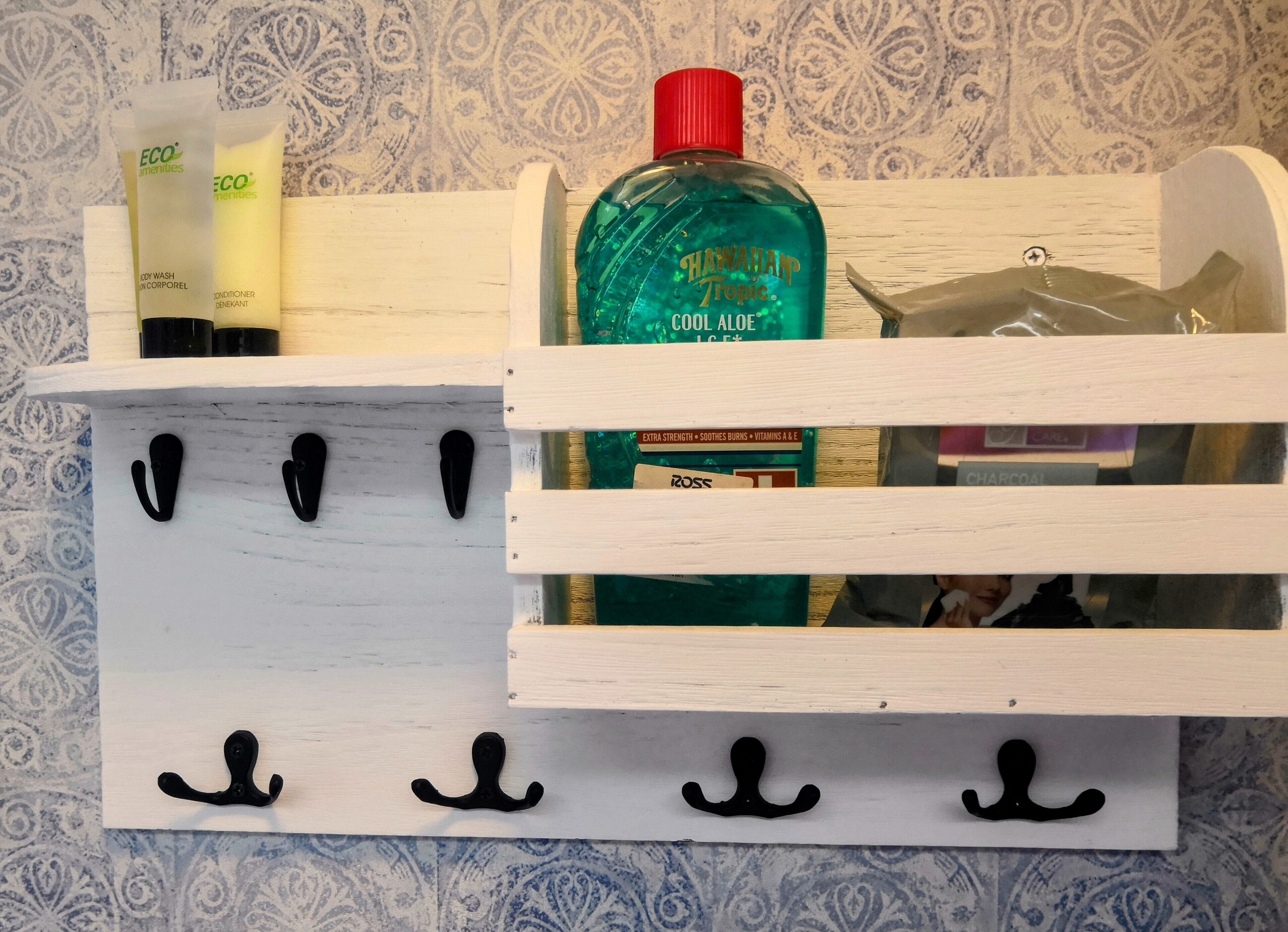 A wooden storage unit with hooks for hanging items, containing toiletry products like body wash, conditioner, and a bottle of aloe vera.