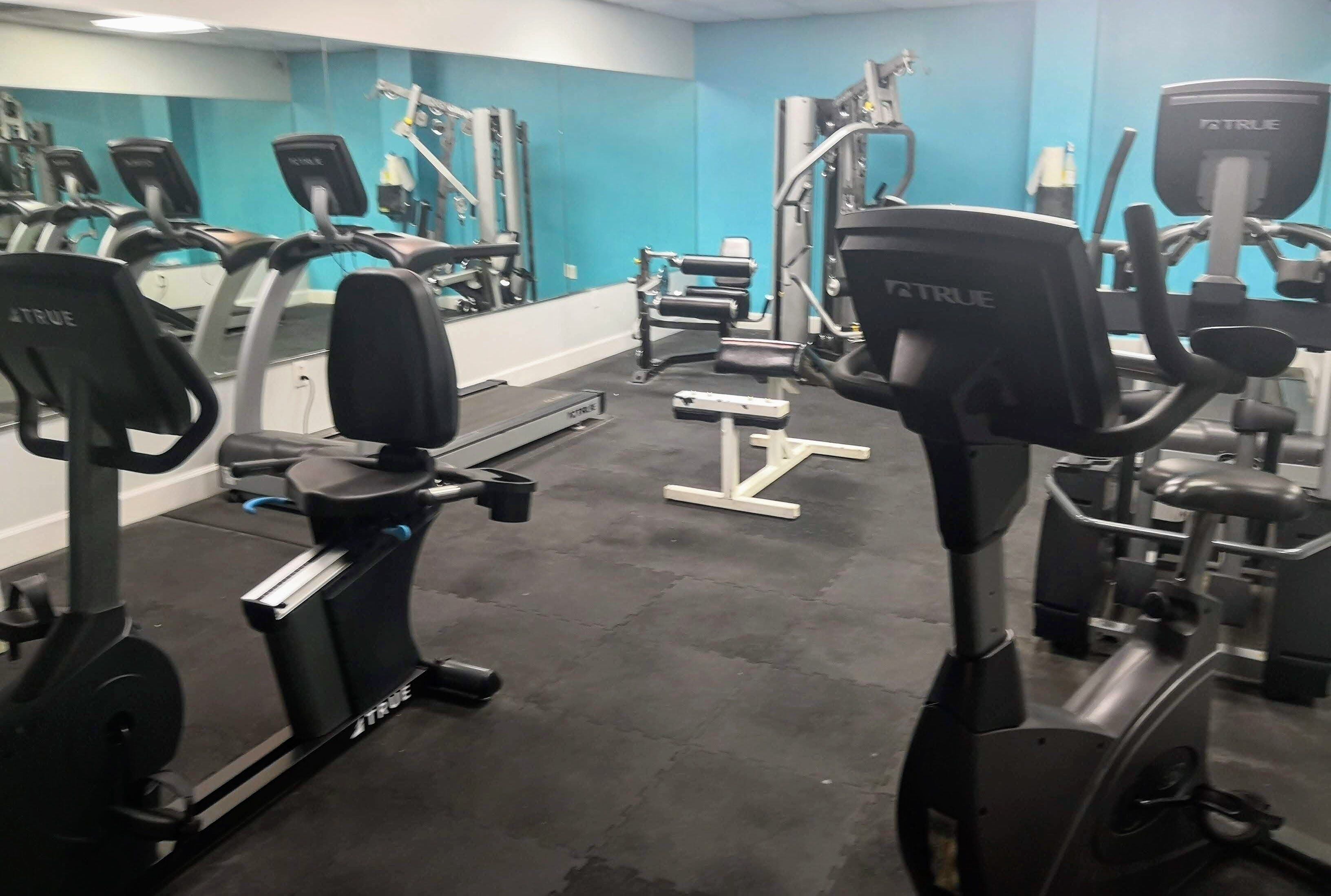 Un gimnasio con diversos equipos de ejercicio, incluyendo cintas de correr y máquinas de pesas.