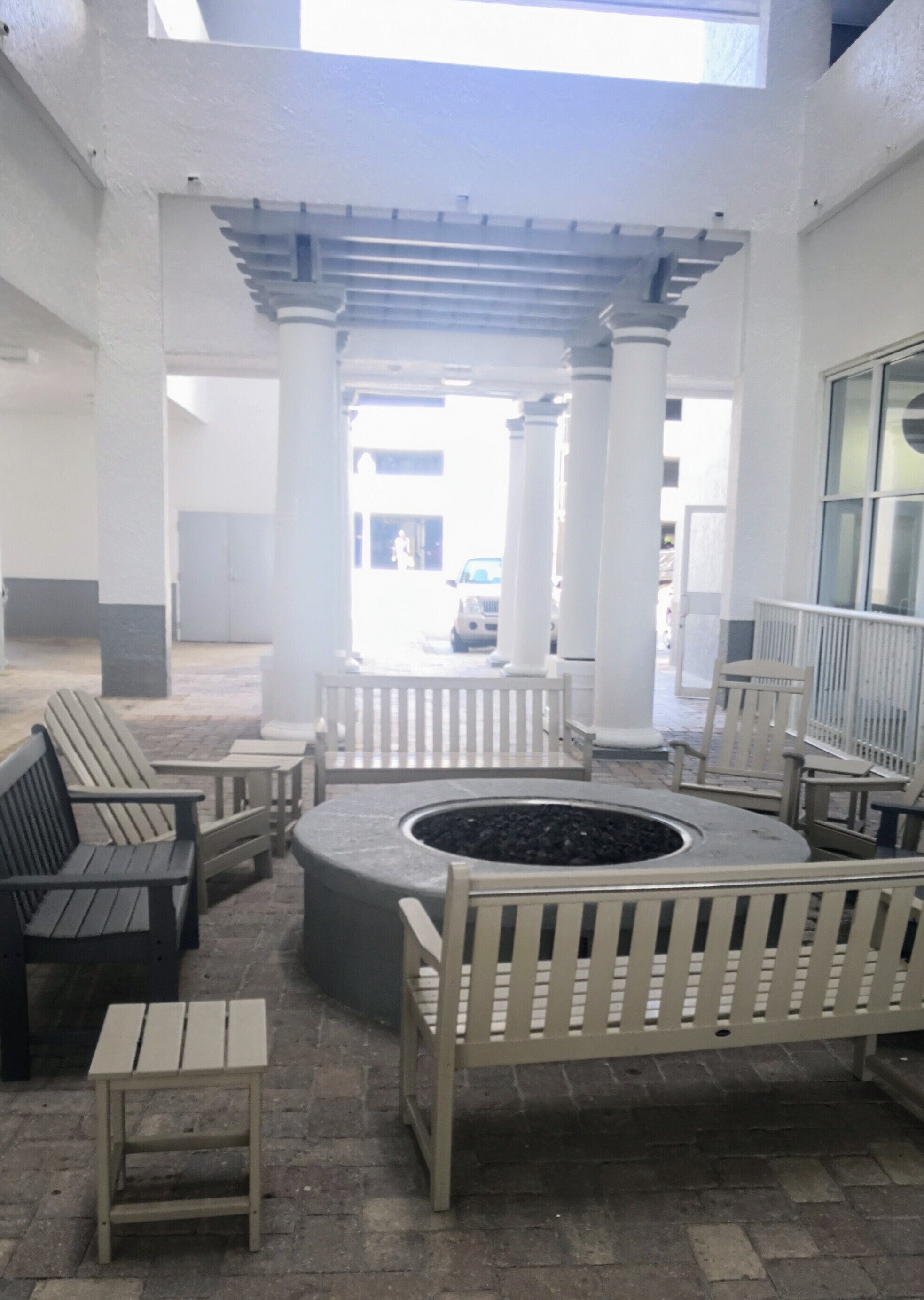 A covered outdoor seating area with benches and a central fire pit.