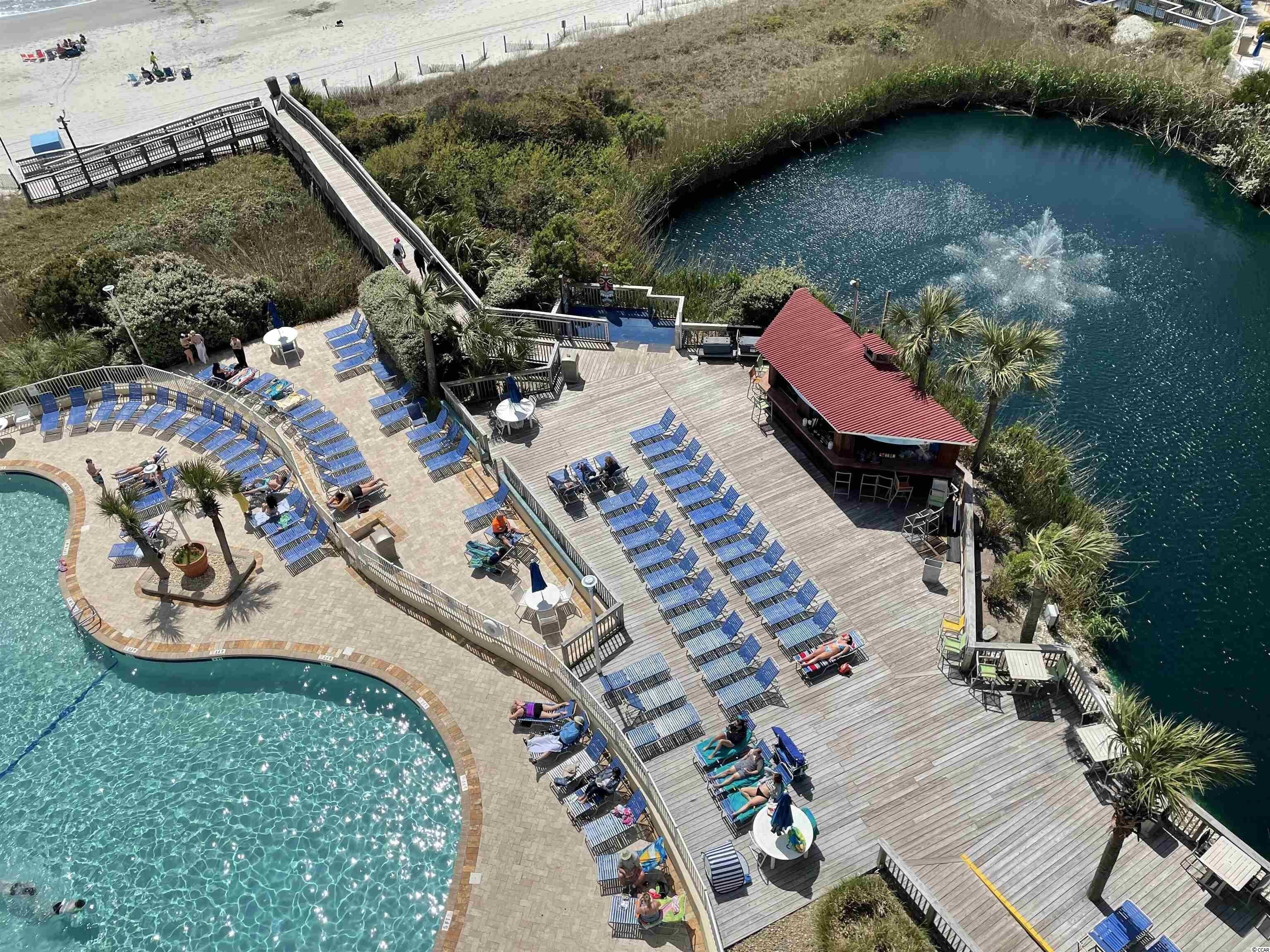 A resort with a pool, lounge chairs, and a building with a red roof.