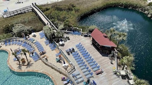 Eine Luftaufnahme eines Resorts mit Pool, Liegestühlen und einem Gebäude mit rotem Dach.