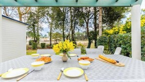 Een buiten eethoek met een tafel voor vier personen, omringd door stoelen, onder een groene pergola.
