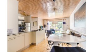 Een moderne keuken met een eethoek, met een houten plafond, een groot raam en uitzicht op de omgeving.