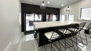A modern dining area with a large marble table, black chairs, and pendant lighting. - ◆DREAM Modern Cabin in the Woods ◆ Hot tub + Sauna (Hunter)