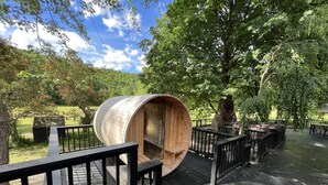 A wooden barrel structure with a spiral staircase, surrounded by a wooden deck and black railings, set in a lush green park. - ◆DREAM Modern Cabin in the Woods ◆ Hot tub + Sauna (Hunter)