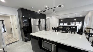 A modern kitchen with a large island, stainless steel appliances, and a dining area with black chairs. - ◆DREAM Modern Cabin in the Woods ◆ Hot tub + Sauna (Hunter)