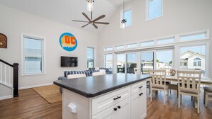 A spacious kitchen with a central island, white cabinetry, and a dining area with wooden chairs and a table. - Upscale Family Home for 10, Community Pool, Grill (Ocean City)