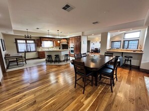 Une cuisine spacieuse dotée d’un plancher en bois, d’un îlot central et d’un coin repas avec des chaises.