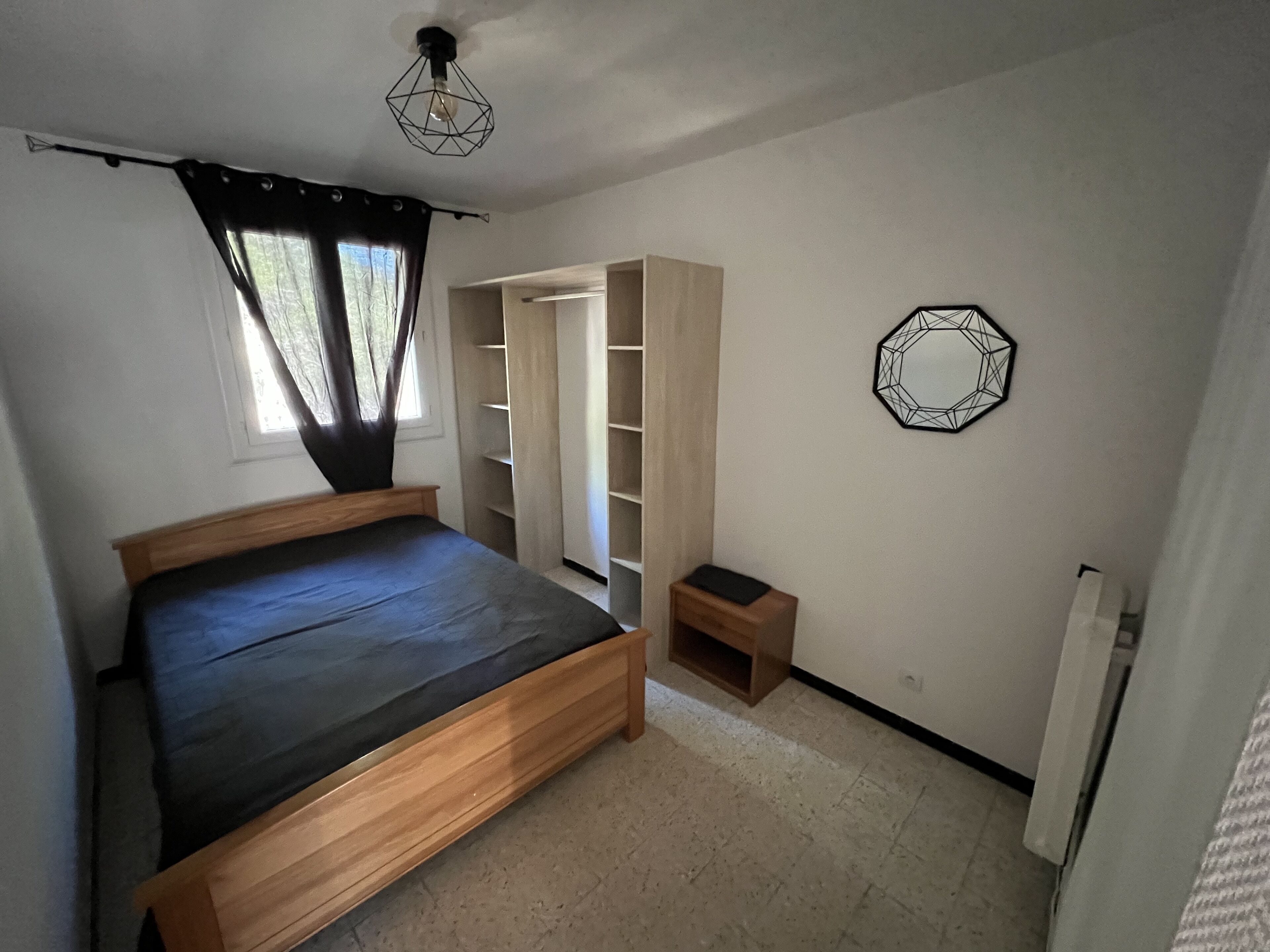 Ein Schlafzimmer mit Bett, Schrank, einem kleinen Tisch und einer Wanddekoration.