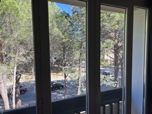 A view through a window with a view of trees and parked cars outside. - Apartment near the beach and shops (Argelès-sur-Mer)