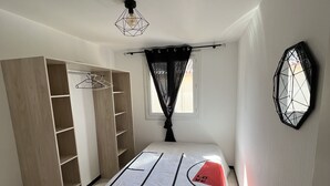 A bedroom with a bed, a wardrobe, a mirror, and a window. - Apartment near beach and shops (Argelès-sur-Mer)