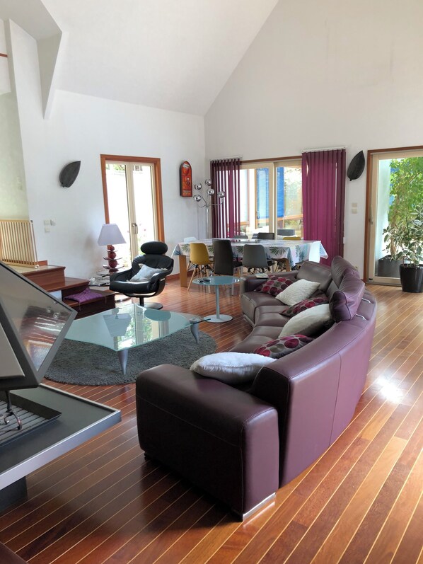 Un salon moderne avec une table basse en verre, un canapé en cuir et un coin repas avec des chaises.