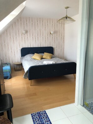 Une chambre avec un lit, une petite table ronde, une chaise et une vue sur l’extérieur.