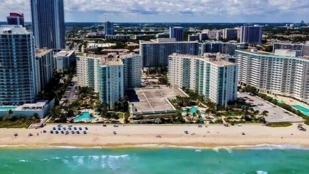 Un paysage urbain côtier avec de hauts immeubles, une plage et un espace piscine.