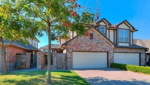 A residential house with a brick facade, a garage, and a well-maintained lawn.