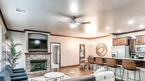 A modern living room with a fireplace, a dining area, and a kitchen.