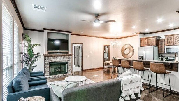 A modern living room with a fireplace, a dining area with bar stools, and a kitchen with wooden cabinets.
