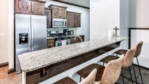 A modern kitchen with a long island, stainless steel appliances, and wooden cabinets.