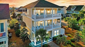 A multi-story residential building with a balcony on the second floor, surrounded by greenery and other houses. - GOLF CART - Heated POOL - 3 Kings/1 Queen - Walk to Beach - 5 Patios/Balconies! (Santa Rosa Beach)