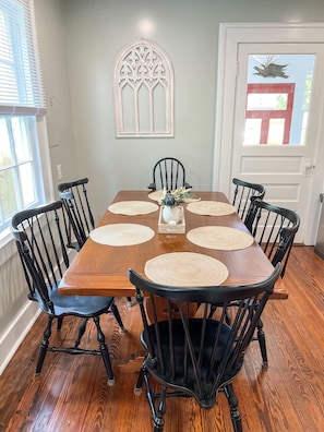 A dining room with a wooden table, black chairs, and a decorative wall piece.