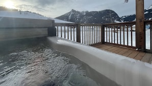 Una terraza de madera con vistas a un paisaje nevado de montaña.