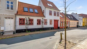 A street with traditional European architecture, including a building with a red-tiled roof and white walls.