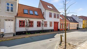 En gade med traditionel europæisk arkitektur, herunder en bygning med rødt tegltag og hvide vægge.