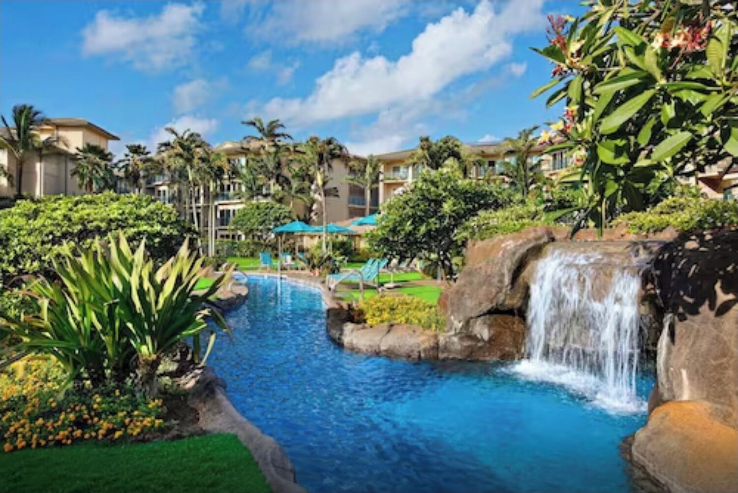 Ein Resort mit Swimmingpool, Palmen und einem Wasserfall.