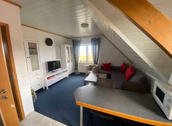 A cozy, well-lit room with a television, seating area, and a dining table.