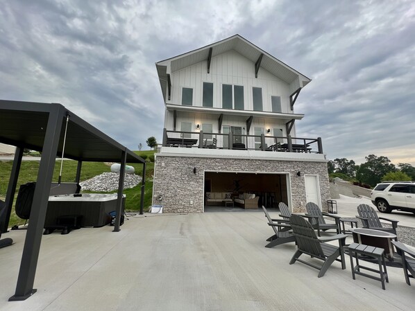 Une maison à deux étages avec un garage, un espace extérieur aménagé pour s’asseoir et une terrasse couverte.