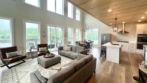 A spacious living area with a large sectional sofa, a dining table, and a kitchen with modern appliances. - Modern Lake Cottage - Amazing Views - 6 Bed/6 Bath - Boat Launch (LaFollette)