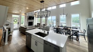 A spacious kitchen with a central island, a dining area with a view, and a fireplace. - Modern Lake Cottage - Amazing Views - 6 Bed/6 Bath - Boat Launch (LaFollette)