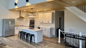 A modern kitchen with a central island, stainless steel appliances, and a wooden ceiling. - Modern Lake Cottage - Amazing Views - 6 Bed/6 Bath - Boat Launch (LaFollette)