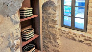 A stone wall with a window and shelves holding woven baskets.