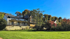 A large house with a stone wall, a glass conservatory, and a well-maintained lawn.