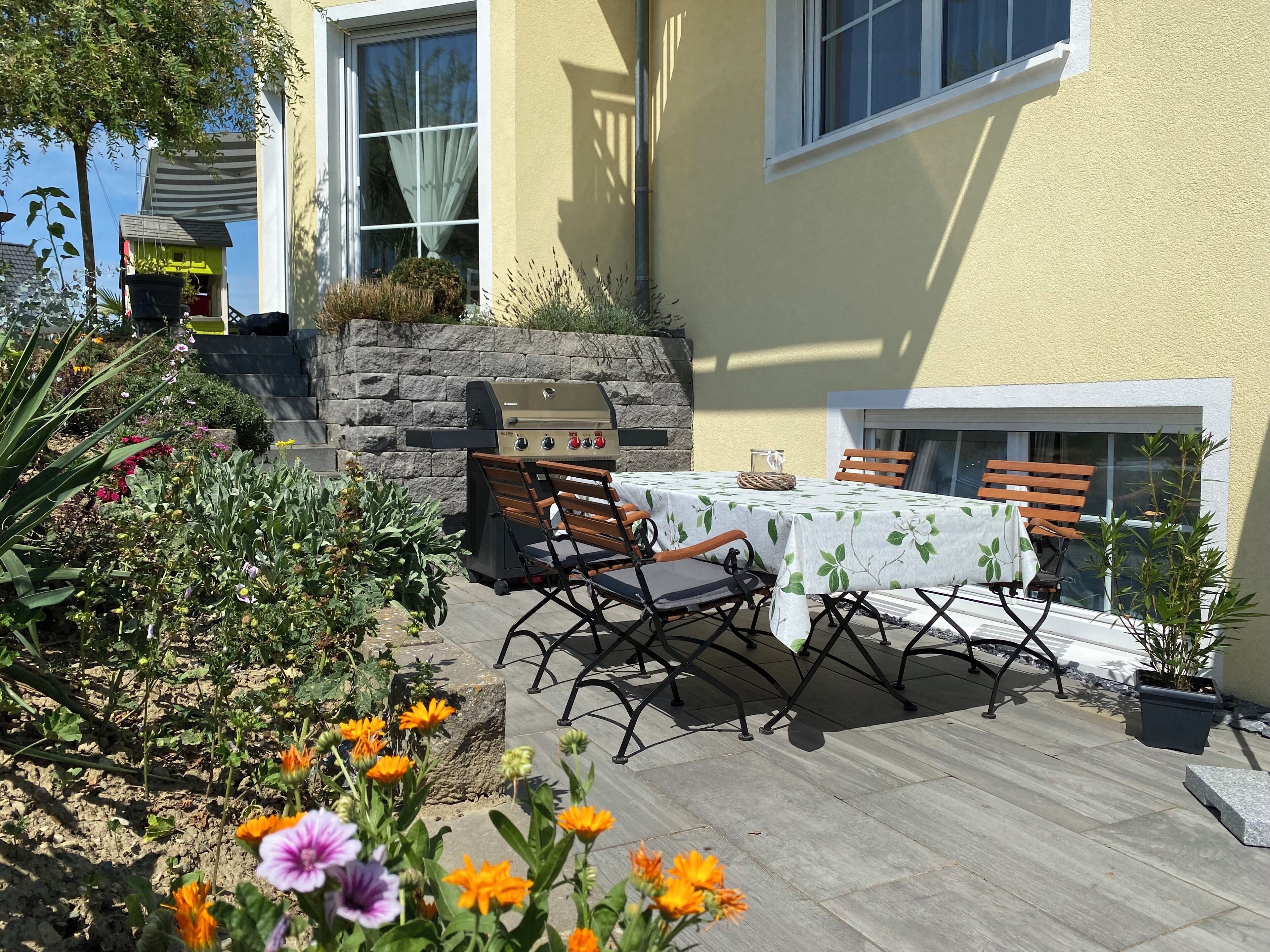 Une terrasse extérieure avec une table, des chaises et un barbecue.