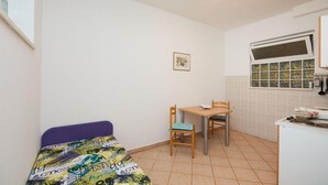 Il s’agit d’une petite pièce, de taille modeste, qui contient un lit, une table et des chaises. Une fenêtre offre une vue sur l’extérieur.