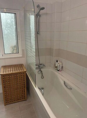 Een bad/douchecombinatie, een bidet, handdoeken, toiletpapier