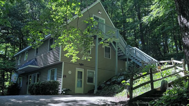 Une maison à deux étages avec un porche à l’avant, un escalier menant au deuxième étage et une allée.