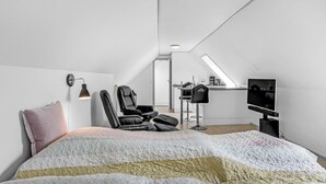 A modern, minimalist bedroom with a large bed, a desk, and a TV. - Cozy apartment in Nexø with WiFi (Nexø)