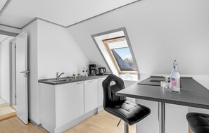 Enjoy a meal for two at the compact kitchen's dining table, equipped with a sink and coffee maker.
