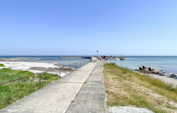 Stroll along the paved walkway to the pier, where boats are docked and a lighthouse stands in the distance.