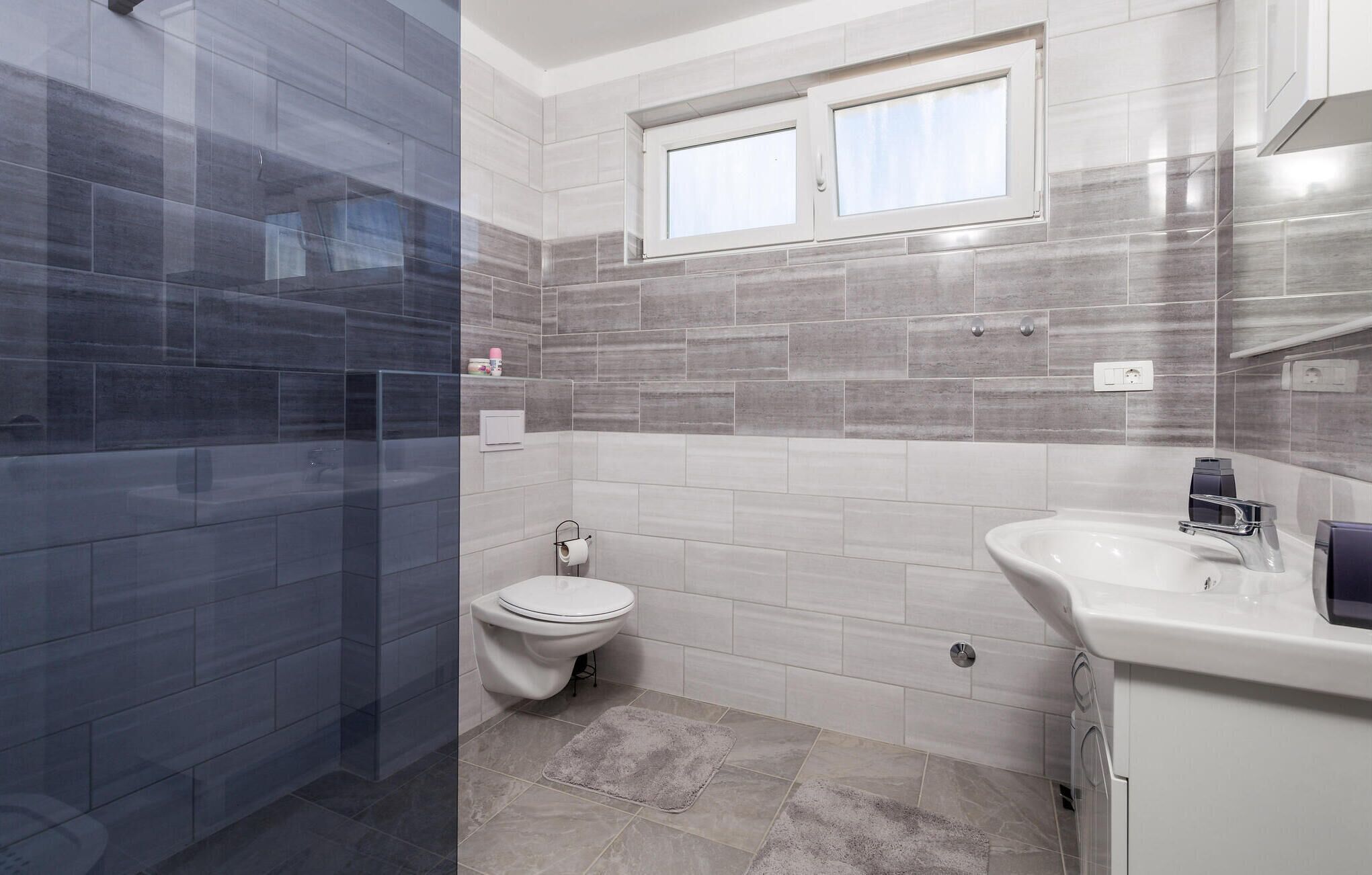 A modern bathroom with a shower, toilet, and sink.
